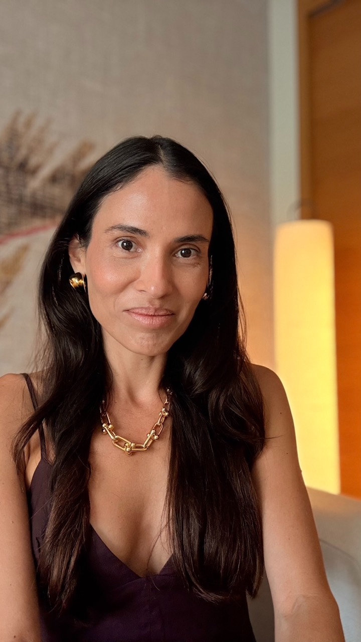 Indoor portrait of Dani Hayoshi with long dark hair, a dark dress and a gold necklace.